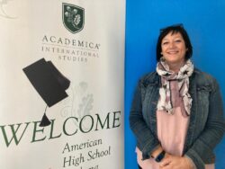 La directora del programa de Bachillerato Dual, María Urquizo, sonríe al lado del cartel de AcademicaSpain