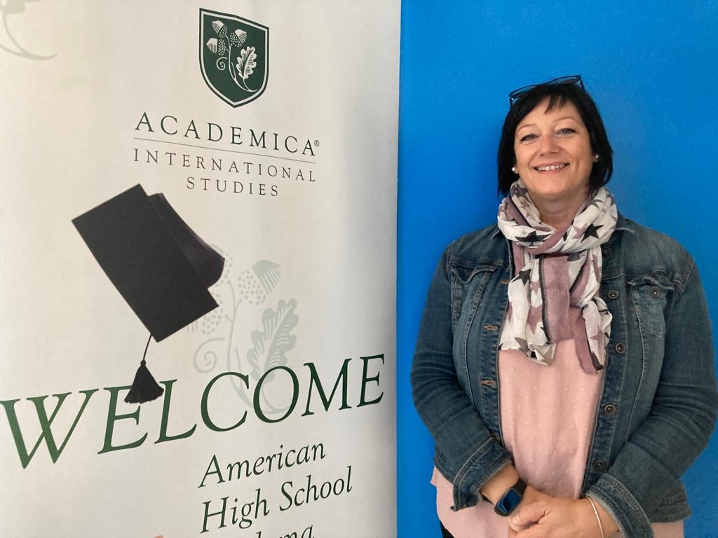 La directora del programa de Bachillerato Dual, María Urquizo, sonríe al lado del cartel de AcademicaSpain